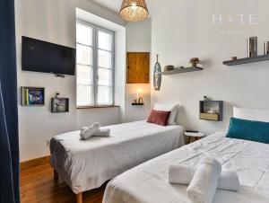 twee bedden in een kamer met een tv aan de muur bij Chaleureux logement-centre ville-proche gare-plage in Les Sables-dʼOlonne