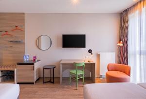 a hotel room with a desk and a tv on the wall at Ramada Encore by Wyndham Munich Messe in Munich