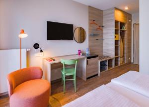 a hotel room with a desk with a television and a bed at Ramada Encore by Wyndham Munich Messe in Munich