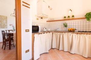 a kitchen with a counter with white curtains on it at Su Trigu, ground floor in Bari Sardo +12 photos