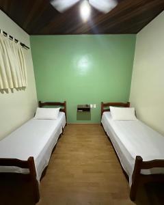 2 camas en una habitación con paredes verdes en Hotel Lara's, en Ribeirão Preto