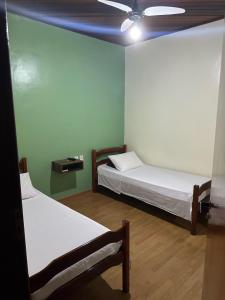 Habitación con 2 camas y ventilador de techo. en Hotel Lara's, en Ribeirão Preto