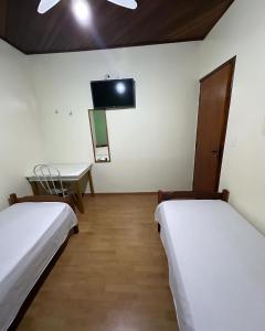 Habitación con 2 camas y TV en la pared. en Hotel Lara's, en Ribeirão Preto
