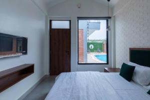 a bedroom with a bed with a television and a window at Tarshal Outhouse to relax in Jaipur in Jaipur