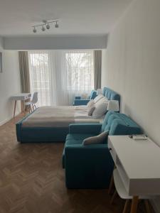 a bedroom with a blue bed and a couch at Apartament Planeta 202 - tylko 100 m do plaży, odnowiony w 2024 in Mielno