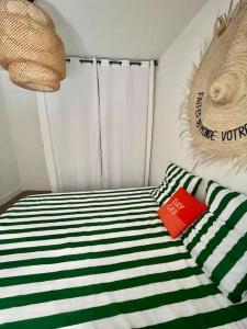 uma cama com lençóis listrados verde e branco e um livro em Casa Pao à 50m de la plage em Cassis