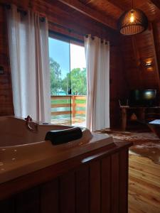 baño con bañera y ventana grande en Cabanas Vida no Campo, en Santa Maria do Erval