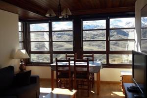 a living room with a table and chairs and windows at Ibones azules in Sallent de Gállego