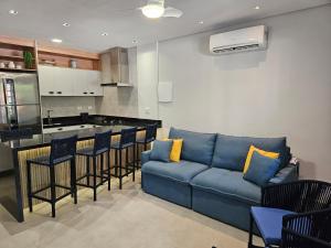 uma sala de estar com um sofá azul e uma cozinha em Flat na Riviera de São Lourenço com serviço de hotelaria em Rivera de São Lourenço