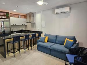 a living room with a blue couch and a kitchen at Flat na Riviera de São Lourenço com serviço de hotelaria in Riviera de São Lourenço