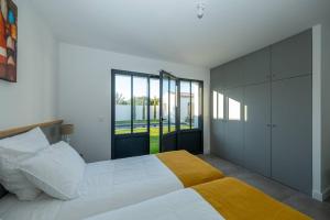 een slaapkamer met een groot wit bed en een gele deken bij Maison familiale neuve avec piscine chauffée in La Noue