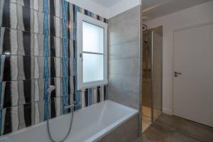 een badkamer met een bad, een raam en een douche bij Maison familiale neuve avec piscine chauffée in La Noue
