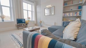 uma sala de estar com um sofá azul e uma televisão em Burlington Mansions - Stunning Coastal Apartment em Bournemouth