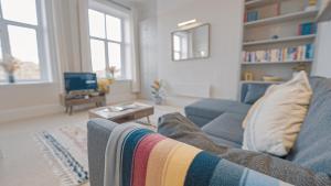 a living room with a blue couch and a tv at Burlington Mansions - Stunning Coastal Apartment in Bournemouth