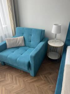 a blue couch in a room with a bed at Apartament Planeta 202 - tylko 100 m do plaży, odnowiony w 2024 in Mielno