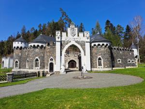 a large stone building with an arch in a park at Hrad Kunzov Glamping & SPA & Restaurant in Přerov