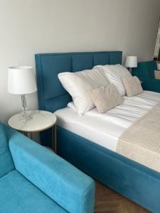 a bed with a blue headboard and a blue couch at Apartament Planeta 202 - tylko 100 m do plaży, odnowiony w 2024 in Mielno