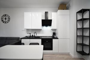a kitchen with white cabinets and a black counter top at RentPlanet - Apartament Bałtycka II in Kołobrzeg