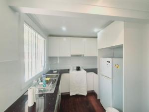 a white kitchen with a sink and a refrigerator at Kaban Power 39 in Bidwill