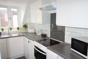 a white kitchen with a sink and a stove at Tulip Place in Chelmsford