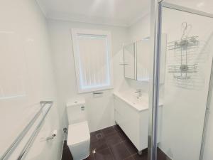 a white bathroom with a toilet and a sink at Kaban Power 39 in Bidwill