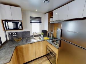 a kitchen with wooden cabinets and a stainless steel refrigerator at Kokua Développement présente MOBIL HOME résidentiel toutes options camping 4 étoiles CANET in Canet-en-Roussillon