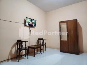 a room with chairs and a tv on a wall at LestInn Homestay Monjali Mitra Reddoorz in Kejayan