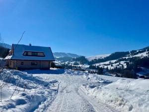uma estrada coberta de neve com uma casa ao fundo em Zrubová chata Panorama Family em Habovka