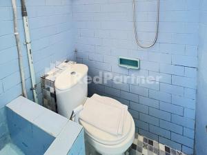 a bathroom with a white toilet and a blue wall at LestInn Homestay Monjali Mitra Reddoorz in Kejayan