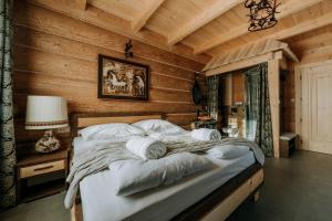 1 dormitorio con 1 cama grande en una habitación con paredes de madera en Gordonówka Grand, en Szaflary