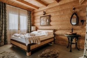 1 dormitorio con 1 cama en una habitación con paredes de madera en Gordonówka Grand, en Szaflary