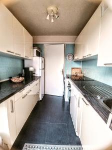 uma cozinha com armários brancos e um piso preto em Appartement cosy centre ville em Sainte-Maxime