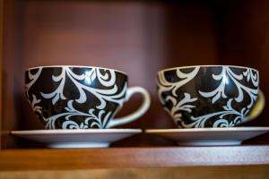 dos tazas de café sentadas en un estante en Apartamenty Pod Ratuszem, en Rzeszów