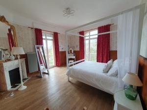 1 dormitorio con cama, chimenea y cortinas rojas en Chambres d'hôtes Villa Honorine, en Saint-Honoré-les-Bains