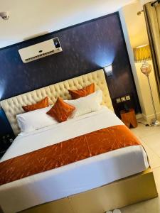 una camera da letto con un grande letto con cuscini arancioni e bianchi di Boun's Hotel a Yaoundé