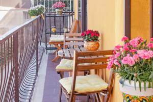 una fila de bancos en un balcón con flores en La Casa Gialla en Taormina