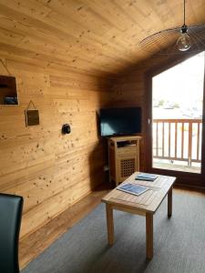 a living room with a wooden wall with a table at 40m2 au pied des pistes Hauteluce les saisies 4 à 6 personnes in Hauteluce