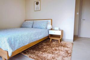 Schlafzimmer mit einem Bett, einem Nachttisch und einem Teppich in der Unterkunft Prime Location Gem Stylish 2BR at Menara Jakarta in Jakarta