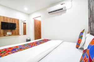 ein weißes Schlafzimmer mit einem Bett und einem TV in der Unterkunft FabHotel Prime Palace View in Vadodara