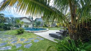 een huis met een zwembad en een palmboom bij Artha Cottages in Sidomukti