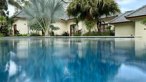 a swimming pool in front of a house with palm trees at Artha Cottages in Sidomukti