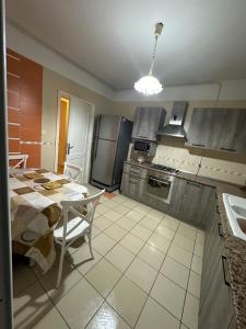 eine Küche mit einem Tisch, einem Kühlschrank und einem Tisch in der Unterkunft Appartement spacieux familial in Le Kram