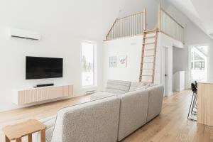 uma sala de estar branca com um sofá e uma televisão em Villas Perspective-Alphonse-Mont-Ste-Anne em Beaupré
