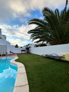 a backyard with a swimming pool and a white fence at Surf&Sleep in Corralejo