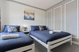 a bedroom with two beds with blue sheets at Mia's House: Park view +Parking in Nottingham