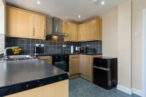 - une cuisine avec des placards en bois et un réfrigérateur noir dans l'établissement Mia's House: Park view +Parking, à Nottingham