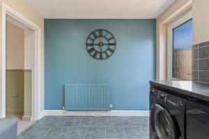 a laundry room with a clock on a blue wall at Mia's House: Park view +Parking in Nottingham