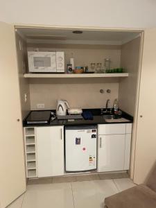 eine kleine Küche mit weißen Schränken und einer Mikrowelle in der Unterkunft Un bonito lugar en el centro de Buenos Aires in Buenos Aires + 26 Fotos