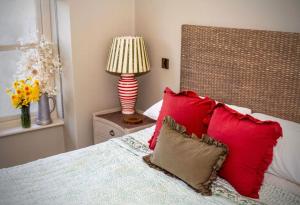 a bedroom with a bed with red pillows and a lamp at Nest Farmhouse in Docking