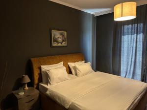um quarto com uma cama com lençóis brancos e almofadas em Misk Hotel & Resort em Tirana